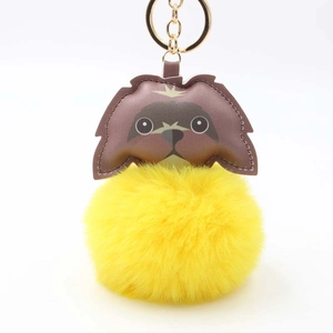 Detail view of cartoon dog leather keychain with fluffy yellow fur pom and gold ring