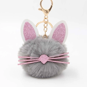 Cute fluffy rabbit fur keychain with pink glitter ears and gold metal clasp on white background