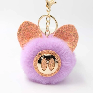 Vue détaillée du porte-clés pompon violet avec oreilles de cochon brillantes et fermoir doré