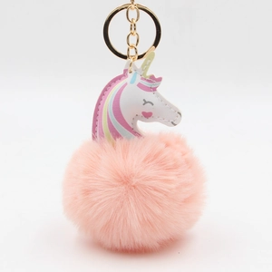 Détail d'un porte-clés licorne en pompon avec boule de fourrure rose et anneau doré