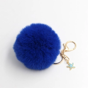 Close-up of royal blue faux fur pompom keychain with golden clip and light blue starfish charm