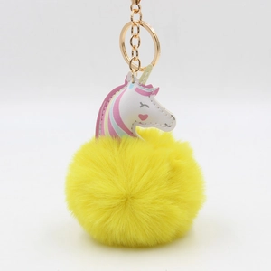 Détail d'un porte-clés licorne en peluche jaune avec anneau doré et touche de cuir coloré