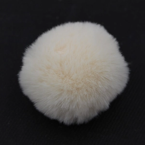 Dettaglio di un morbido pompon in finta pelliccia beige per borse e portachiavi alla moda