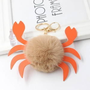 Dettaglio del portachiavi a granchio con pompon in ecopelliccia beige e chele arancioni
