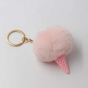 Detail of pink faux fur pompom ice cream keychain with golden metal ring and textured cone