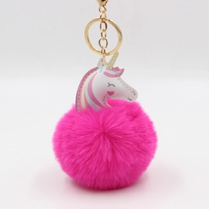Détail d'un porte-clés licorne en peluche rose avec pompon et fermoir en métal doré