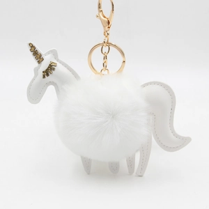 Unicorn plush ball keychain with white faux fur and golden glitter horn on white background