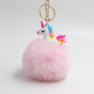 Dettaglio di un portachiavi pompon rosa con unicorno 3D, criniera arcobaleno e anello dorato