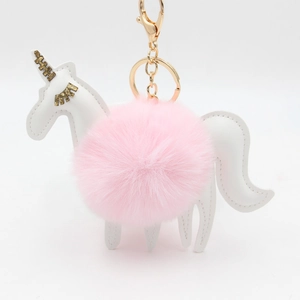 Close-up of plush unicorn keychain with pink fur ball and golden metal lobster clasp