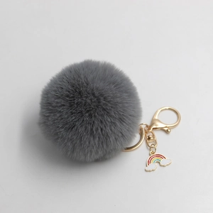 Detail of grey faux rabbit fur pompom keychain with golden alloy hook and rainbow cloud charm