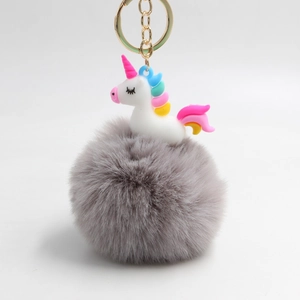 Dettaglio del ciondolo unicorno in resina bianca con pompon grigio e portachiavi dorato
