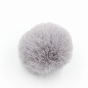 Dettaglio di un pompon in finta pelliccia grigio-viola chiaro con una consistenza soffice