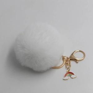 Close-up of white fluffy plush faux fur keychain with gold ring and rainbow charm
