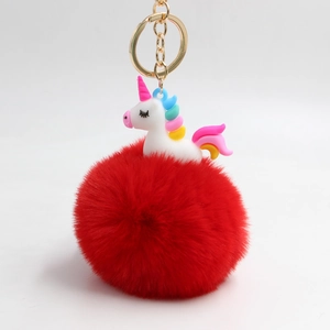 Dettaglio del pompon rosso morbido e ciondolo a forma di unicorno su portachiavi dorato