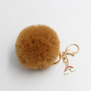 Detail of khaki faux fur pompom keychain with golden clasp and rainbow charm