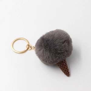 Detail of grey fluffy faux fur pompom ice cream keychain with brown cone and gold clasp
