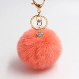 Plush starfish keychain with coral faux fur ball and golden lobster clasp on white background