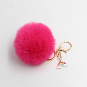 Detail of plush fuchsia faux fur keychain with golden clasp and cute rainbow charm