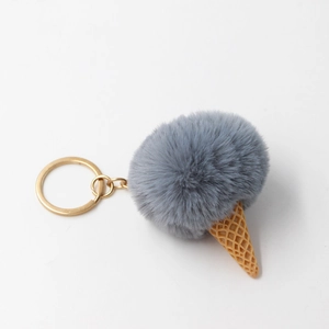Detailed macro view of gray faux fur pompom ice cream keychain with gold ring