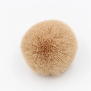 Dettaglio di un pompon in peluche marrone chiaro per accessori di borse e abiti