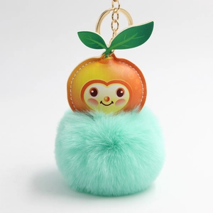 Macro detail of cartoon orange faux leather top with mint green fluffy plush ball keychain