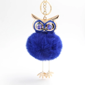 Detailed close-up of blue faux fur owl keychain with gold metal top and purple gem eyes