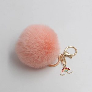 Detail of pink faux fur pompom keychain with golden clasp and rainbow cloud charm