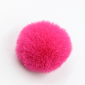 Dettaglio di un pompon in finta pelliccia rosso rosa per borse e accessori moda