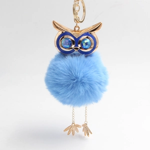 Detail of light blue fluffy owl keychain with gold hardware and sparkling gemstone eyes