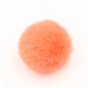 Dettaglio del pompon soffice in finta pelliccia arancione corallo per borse