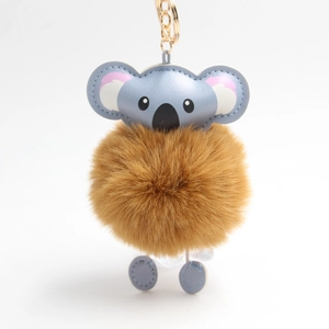 Cute koala pom pom keychain with brown faux fur and blue leather accents on gold metal chain