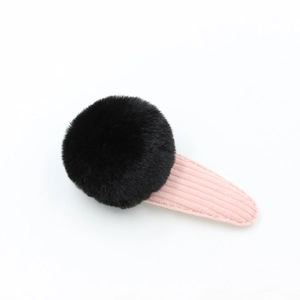 Gros plan sur un pompon noir en fausse fourrure sur pince à cheveux en velours rose