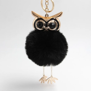 Detail of owl keychain with golden metal head and fluffy black faux fur pompom ball