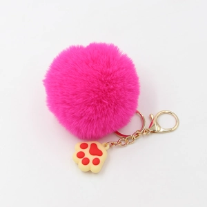 Vue détaillée du porte-clés pompon rose pelucheux avec clip doré et breloque patte