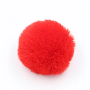 Dettaglio di un pompon di pelliccia sintetica rosso acceso per portachiavi su bianco