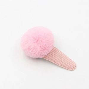 Gros plan d'une pince à cheveux pompon rose en peluche avec texture velours sur la base BB