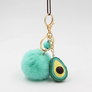 Detailed view of mint green faux fur pompom keychain with cute avocado charm and golden bell