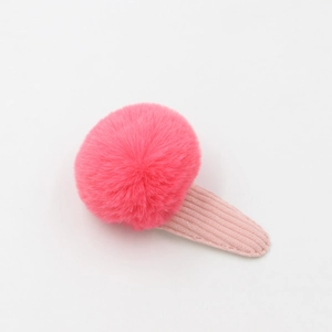 Vue détaillée d'une pince à cheveux pompon rose en peluche avec un tissu rayé doux
