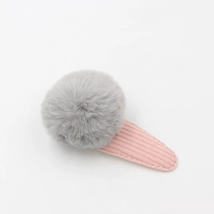 Détail d'une pince à cheveux pompon gris en peluche avec base en velours côtelé rose