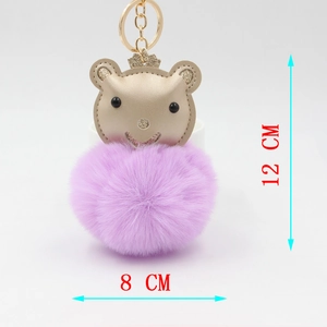 Détail d'un porte-clés boule en peluche violette avec tête d'ours et couronne dorée