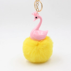 Detail of pink swan with crown and fluffy yellow faux fur pompom on gold keychain