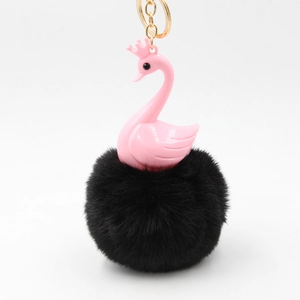 Close-up of pink swan keychain with black faux fur pompom and golden crown detail