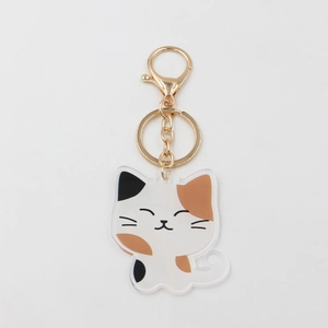 Detail of calico cat acrylic keychain with golden lobster clasp on white background