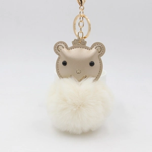 Détail du porte-clés pompon crème avec tête d'ours couronne et anneau doré brillant
