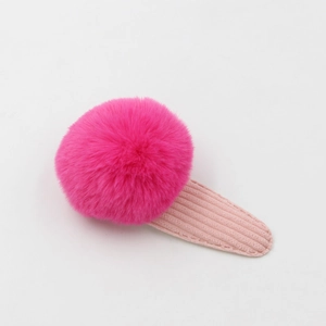 Détail d'un pompon en peluche rose fuchsia avec base de clip en velours côtelé rose clair