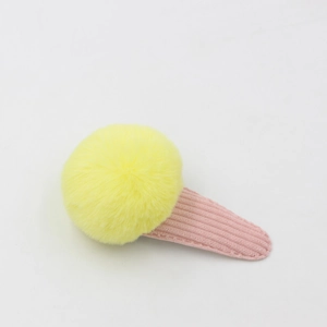 Détail de la pince à cheveux glace avec pompon jaune et base en velours côtelé rose