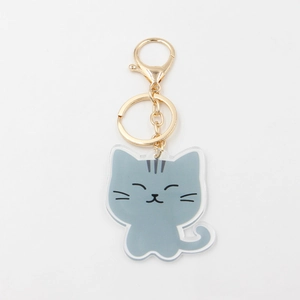 Close-up of cute cartoon grey cat keychain made from translucent acrylic with gold metal hook