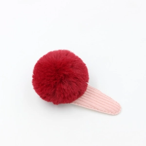 Détail d'une pince à cheveux pompon en peluche avec texture velours et clip robuste