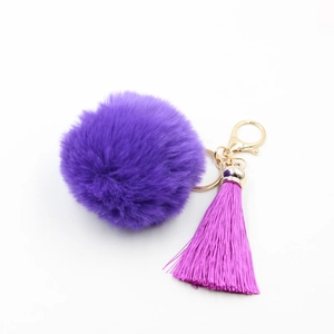 Vue détaillée d'un porte-clés pompon violet avec frange rose vif et fermoir mousqueton doré