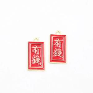 Detail of red enamel charms with gold frame and Chinese lucky text for wealth and prosperity
